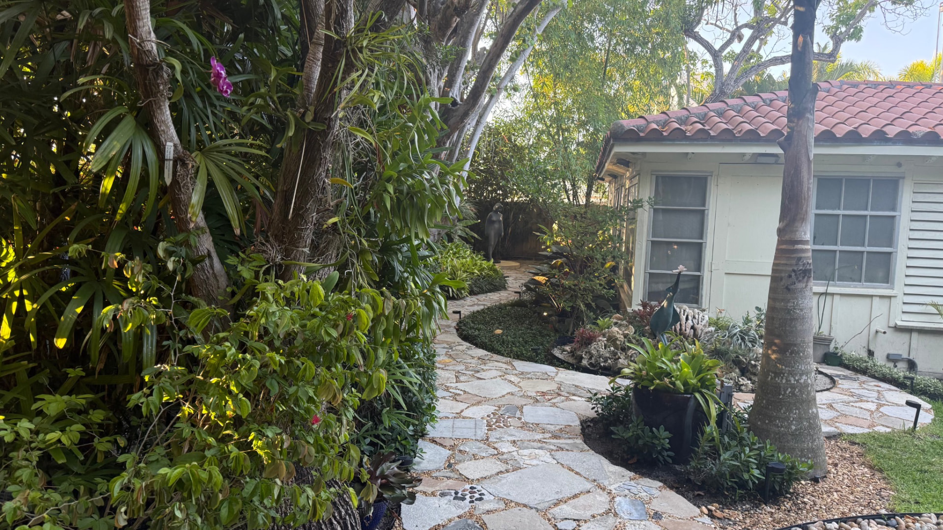 Natural stone garden walkway winding between tropical planting and a residential building
