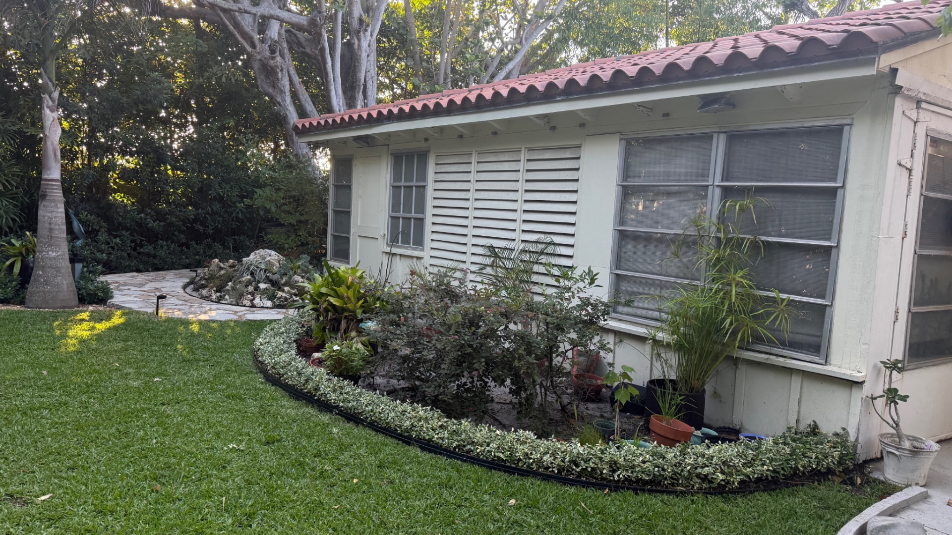 Maintained lawn and curved tropical planting bed beside a Palm Beach area residence
