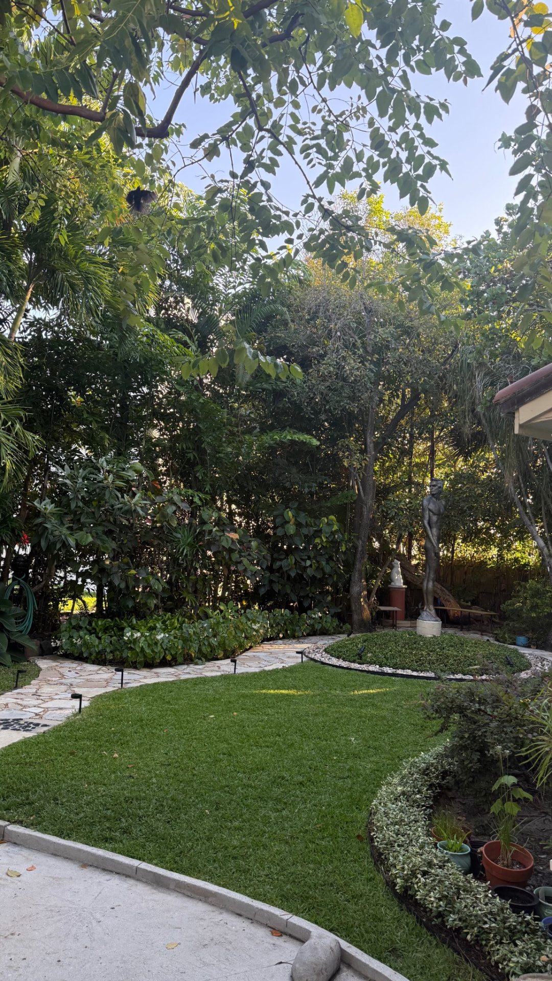 Residential garden composition with mature trees, clipped lawn, planting beds and stone paths