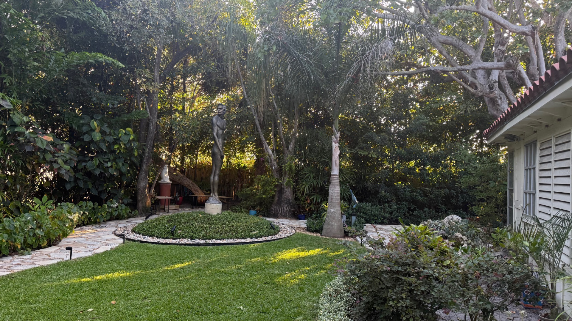 Maintained residential landscape with lawn, palms, shaped beds and intersecting stone pathways